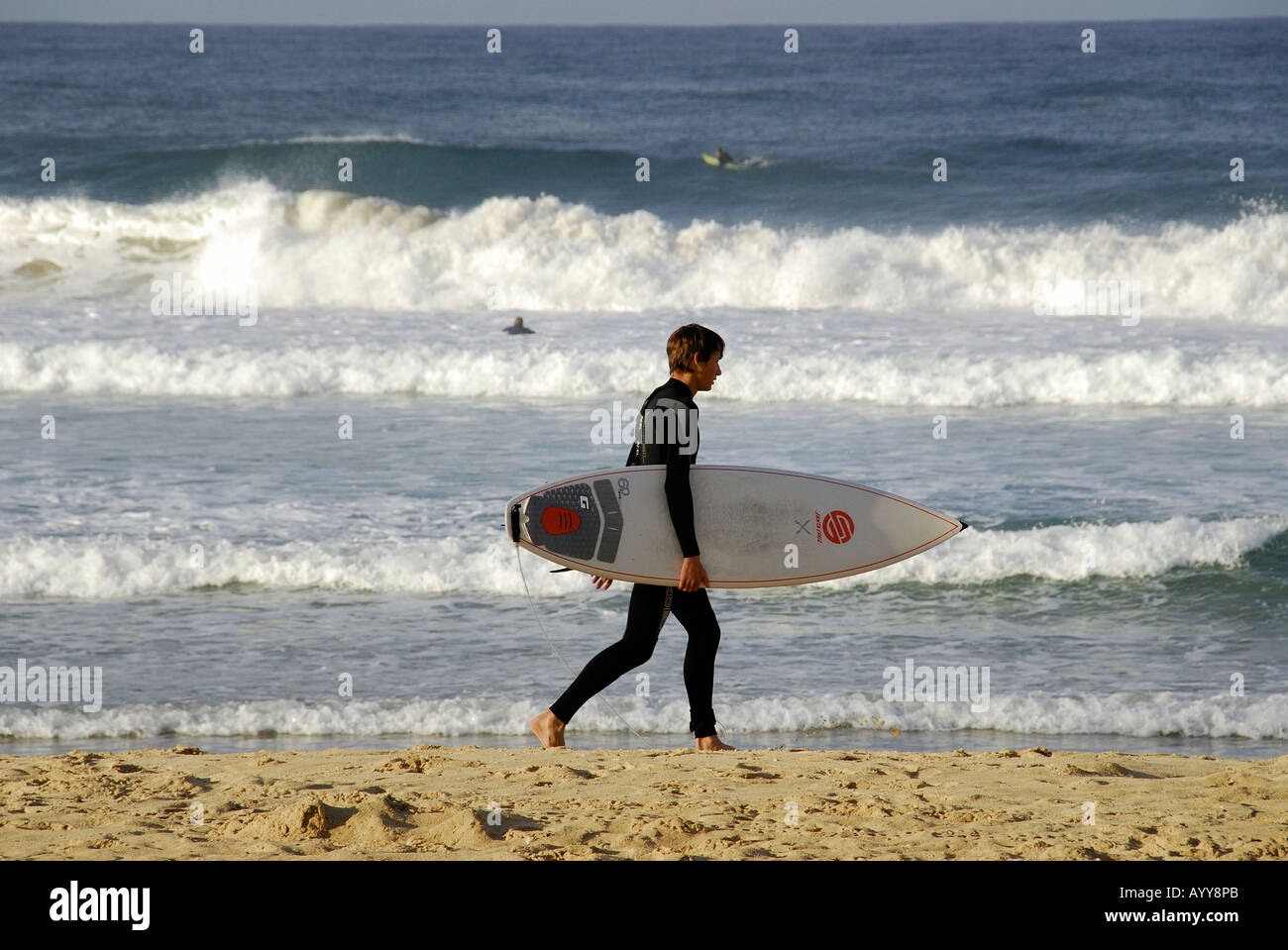 a surfer walking on the beach Stock Photo