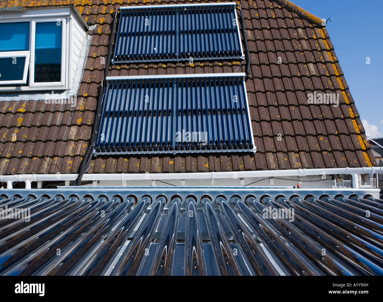 Solar thermal evacuated collecting tubes on a flat roof and a pitched roof used to heat hot water in a Weymouth guest house Stock Photo