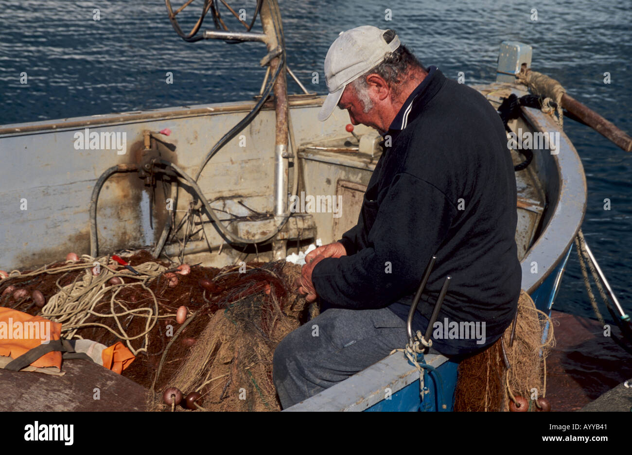 Commercial Fisherman mending nets harbor Porto Azzurro Island Elba Italy Stock Photo
