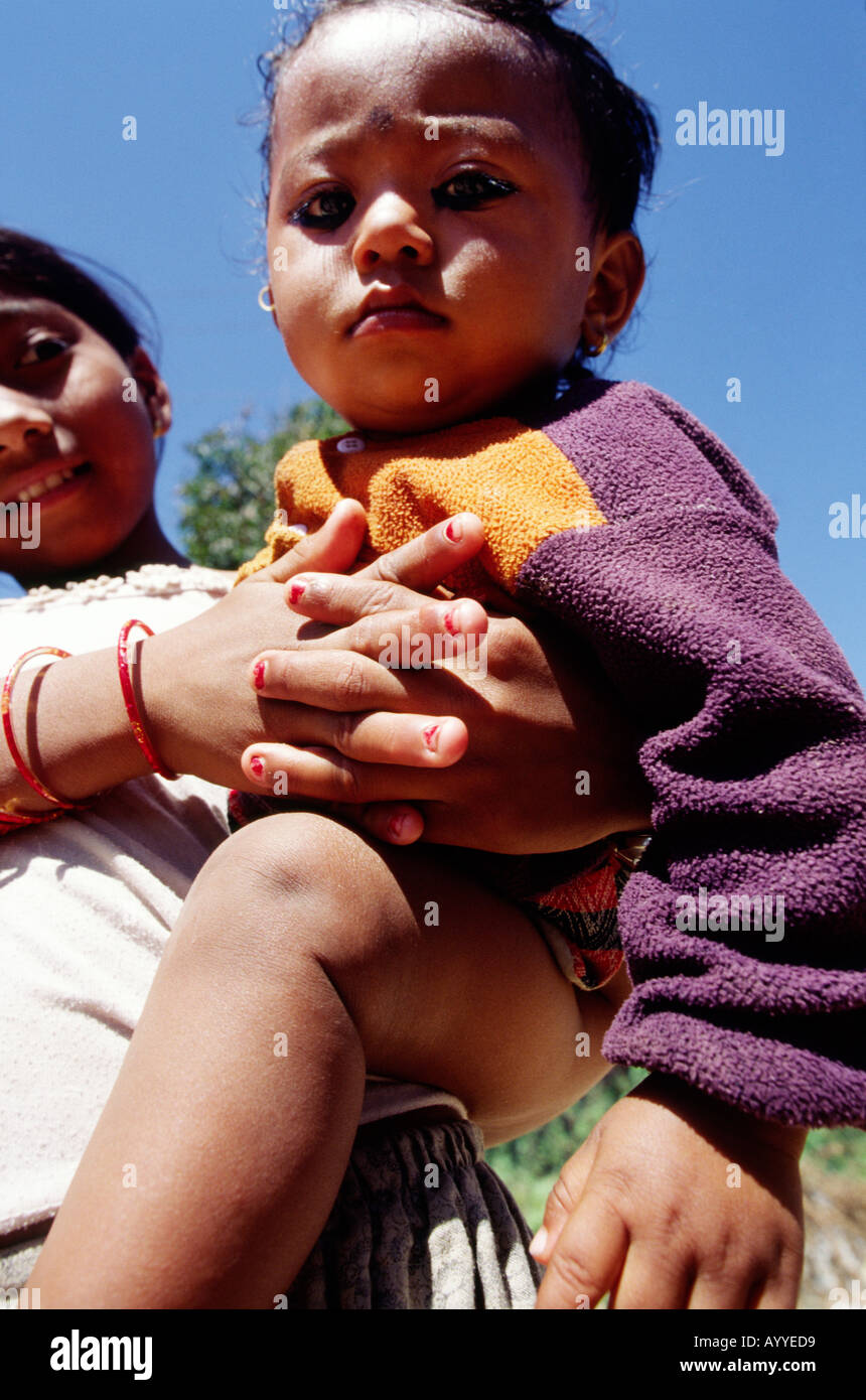 Young Nepalese girl holding her toddler brother in her hands outside