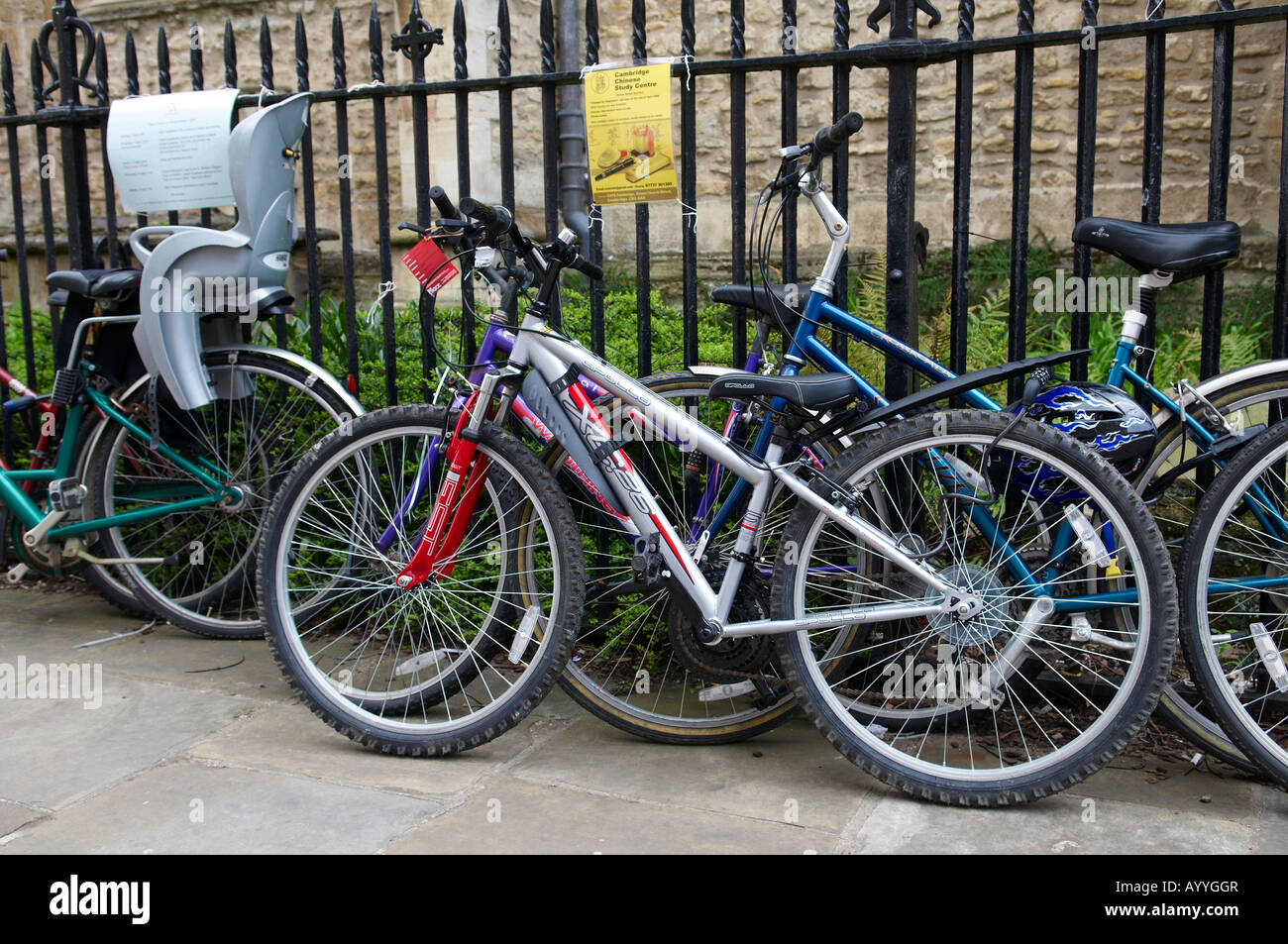 Cycles propped up against a iron fence in Cambridge Stock Photo