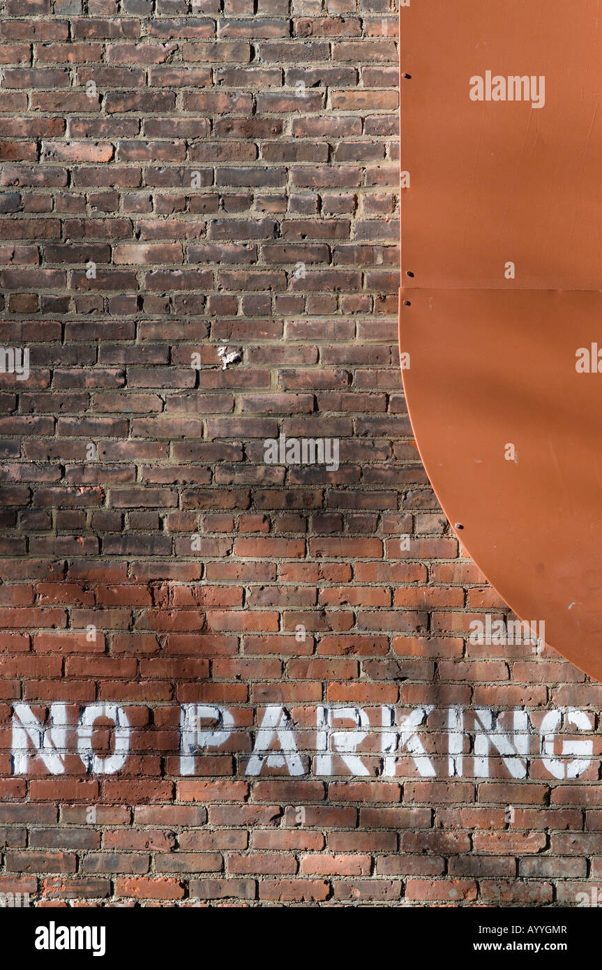 "No parking" spray painted on a brick wall with an outside heating duct