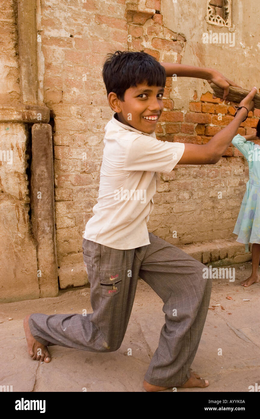 Barefoot Indian male child looking at camera and smiling with cricket