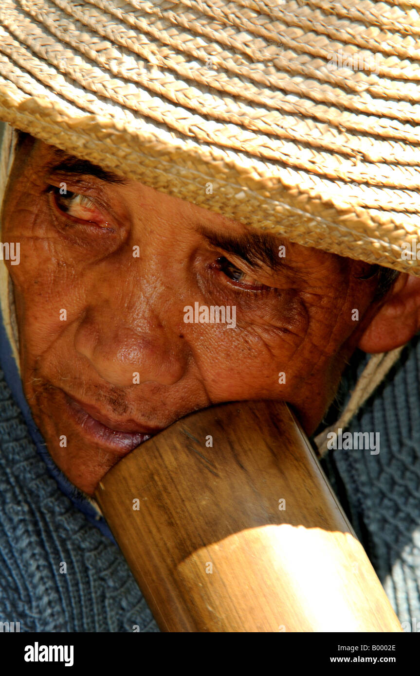A Hani Akha man smokes through the big bamboo pipe Stock Photo