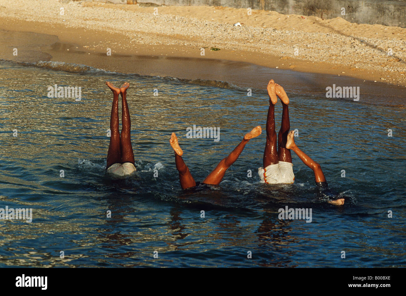 Boys playing in the water show only their feet as they dive in the Cayman Isles. Stock Photo