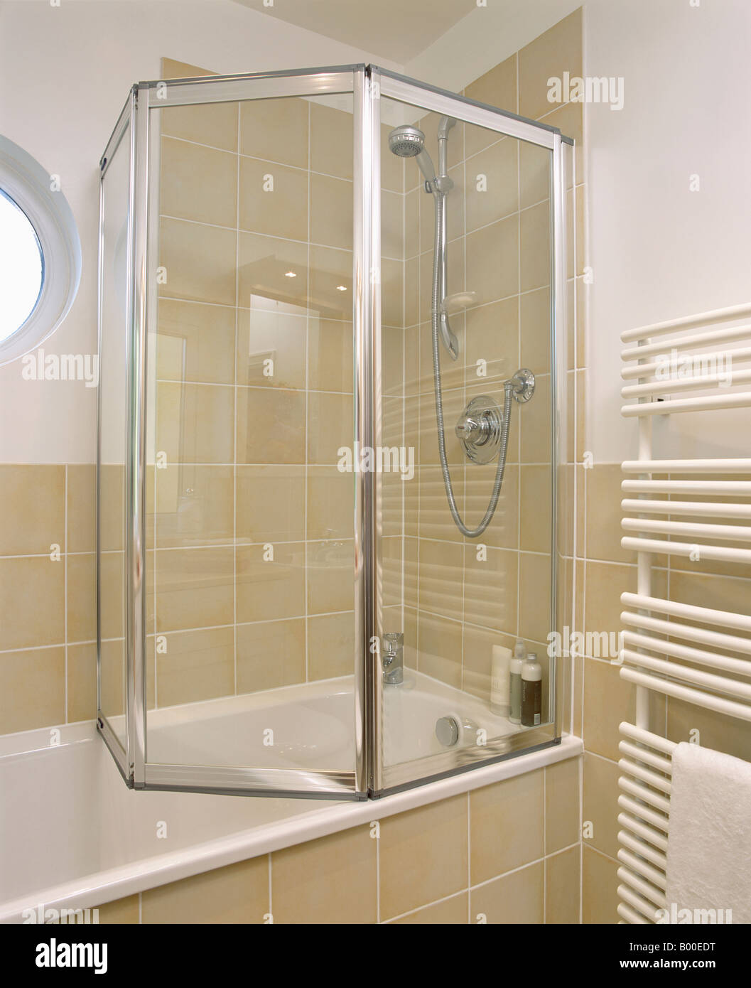 Folding Glass Shower Doors On Bath In Modern Bathroom With Neutral Wall Tiles Stock Photo Alamy