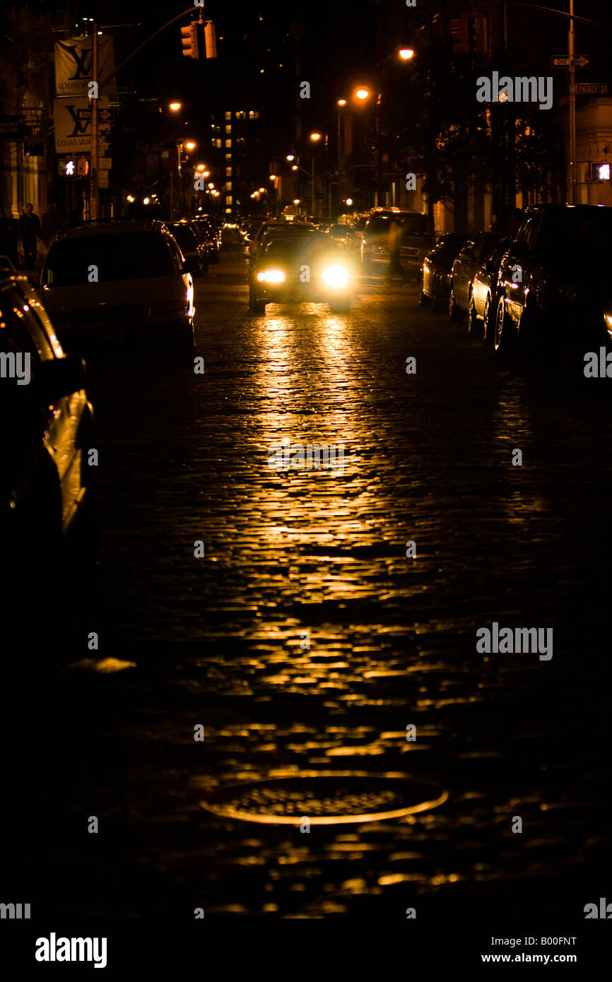 Reflection of a car head-lights in the cobblestone-road on one of the streets of Downtown Manhattan, NY, USA Stock Photo