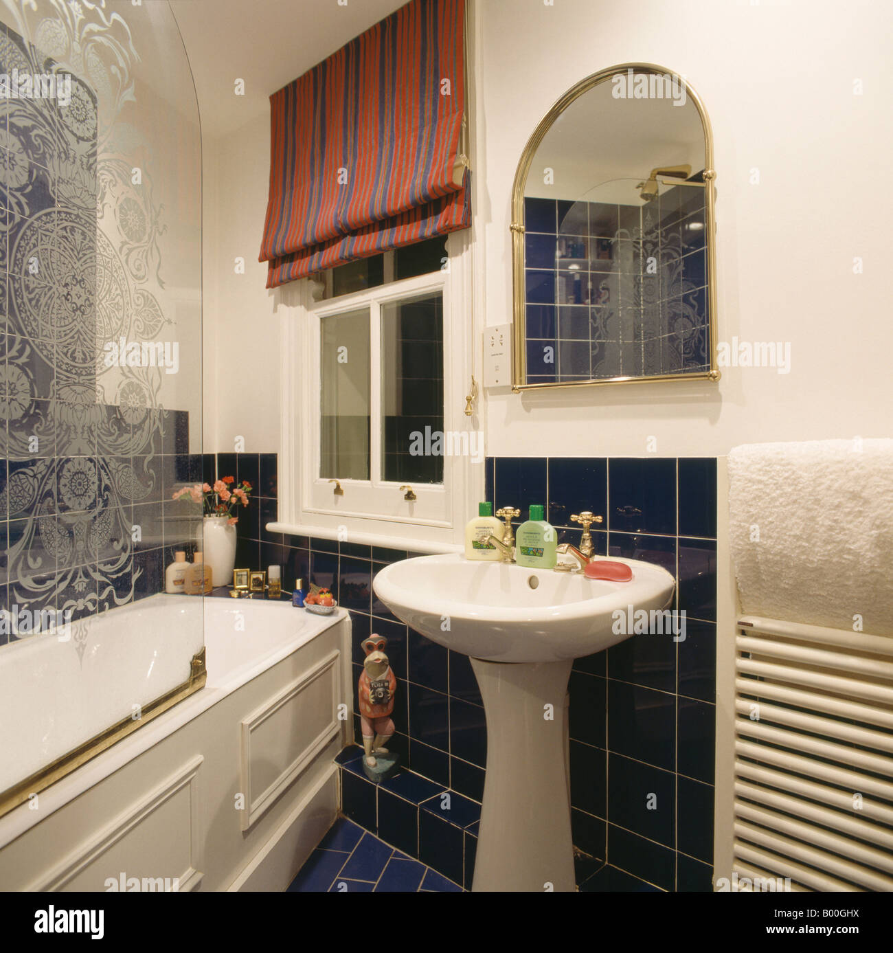 Red and blue striped blind on window of small bathroom with white