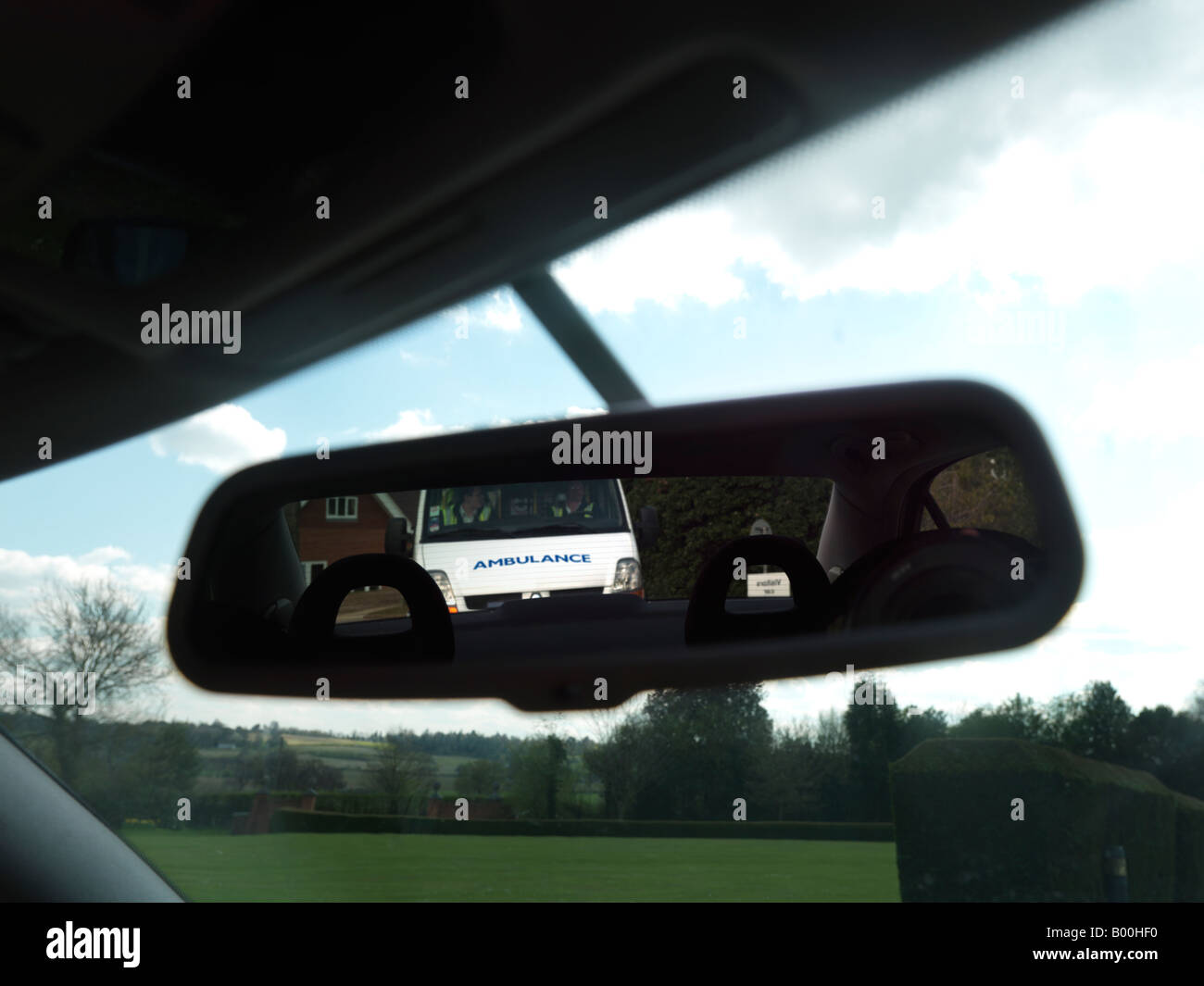 Ambulance seen from a rear View Mirror of a Car Showing Reversed Writing Stock Photo