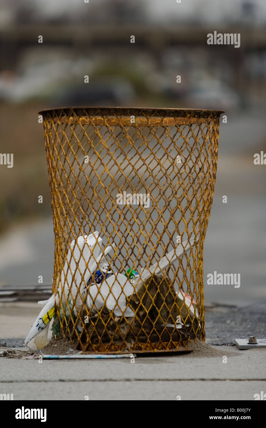 Typical New York City garbage can, with garbage falling out of it. Far