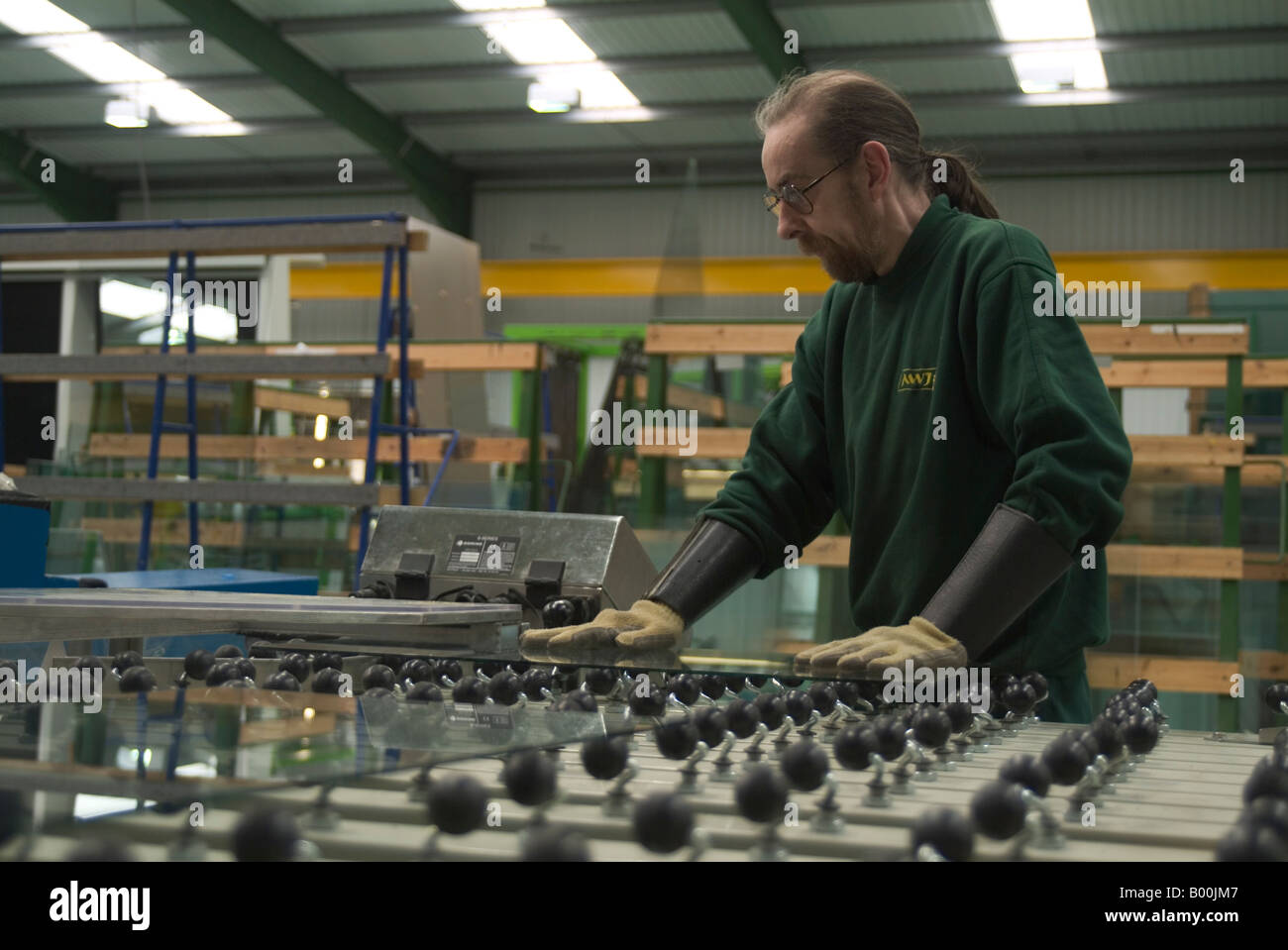 Factory worker applying kite mark to toughened glass in glass factory