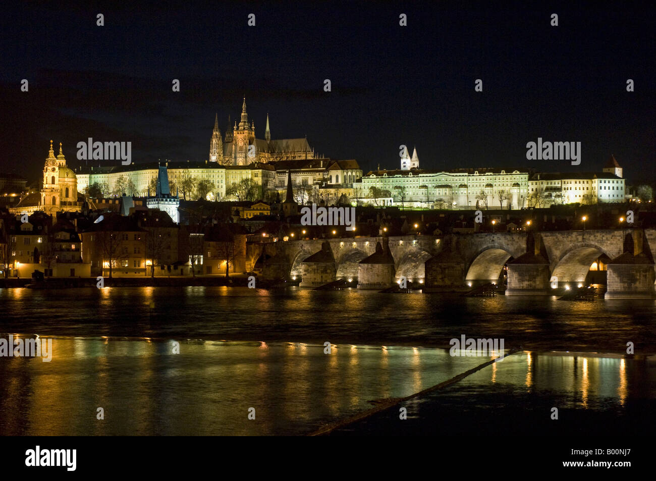 A night view of Saint Vitus's Cathedral located within the grounds of Prague Castle and the Charles Bridge in the foreground. Stock Photo