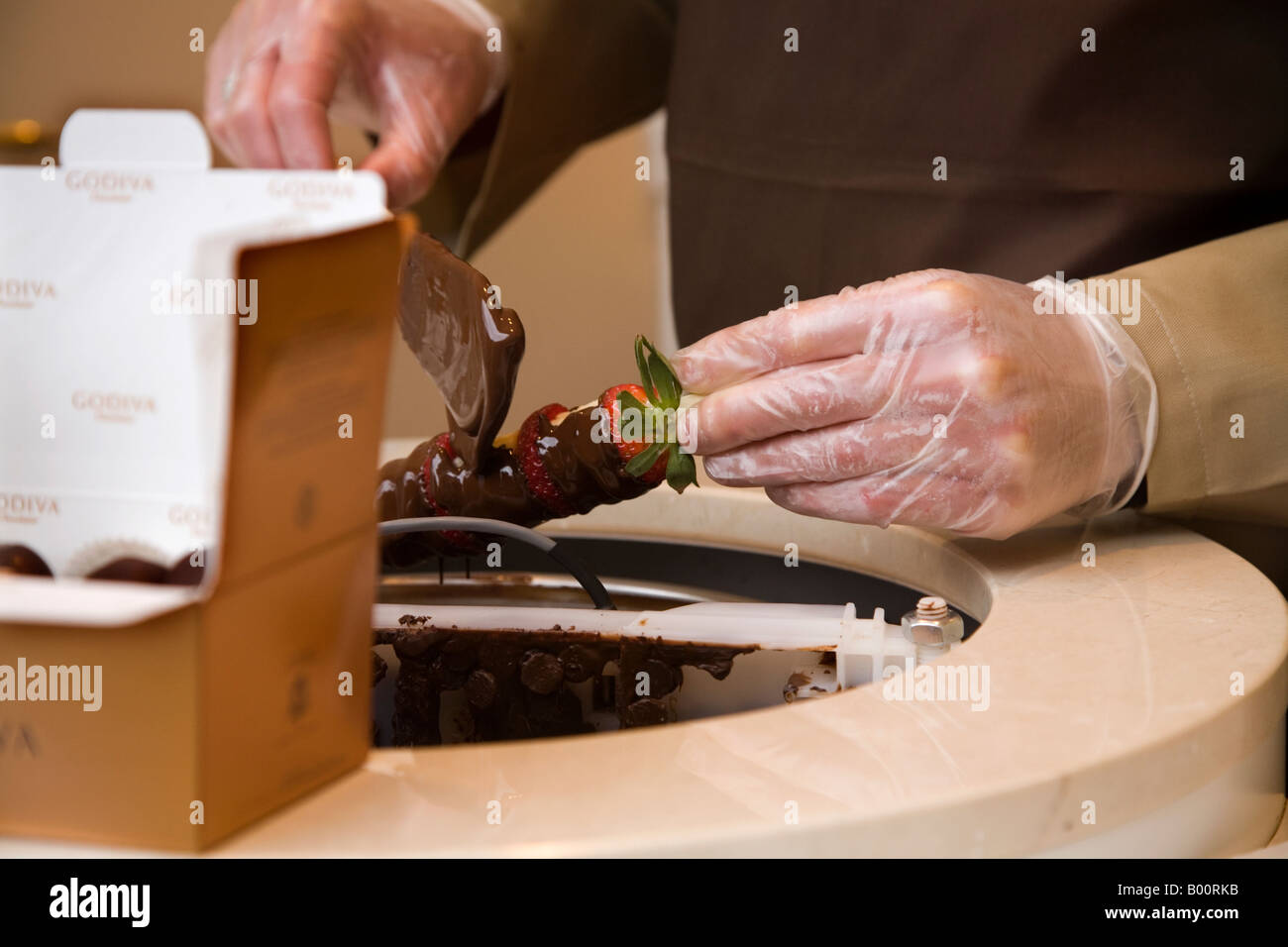 The hands of a chocolatier run chocolate over fresh strawberries. Godiva, Grand Place, Brussels