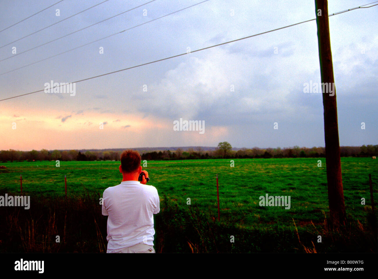 Storm chaser watches intently while shooting video of this tornado near Searcy, Arkansas on April 2, 2006. Stock Photo