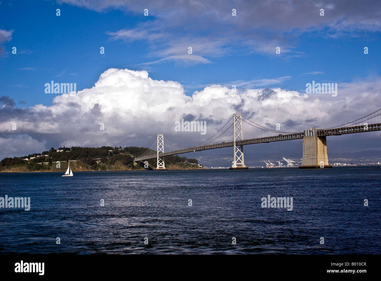 Distant view of SF Bay Bridge with a lone sailboat. Stock Photo