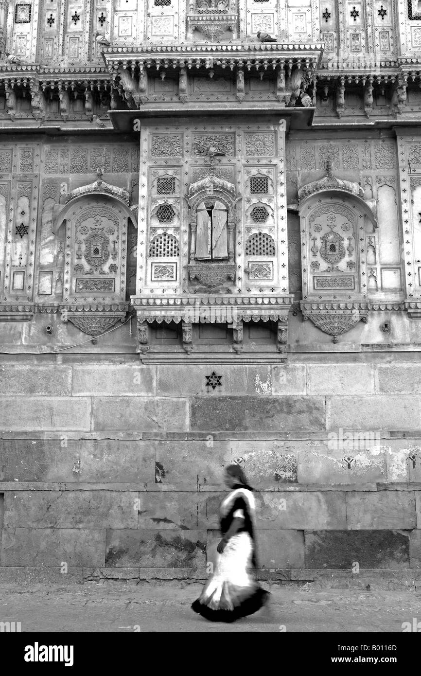 India, Rajasthan, Jaisalmer. On the outside walls of the city's largest haveli, street life goes on as normal. Stock Photo