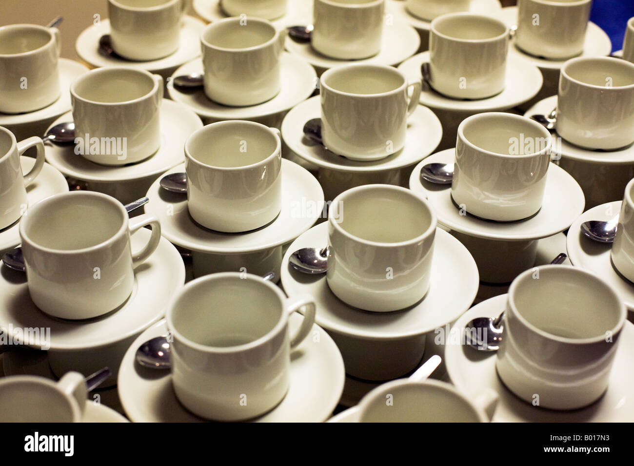 Many tea cups with spoons on saucers. Stock Photo