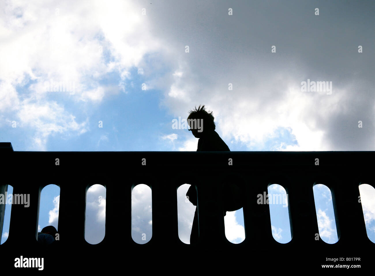 Silhouette of a person walking across bridge before storm hits Stock ...