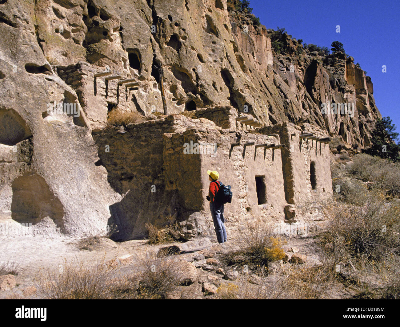 A hiker examines ancient Anasazi Indian cliff houses in Bandelier in