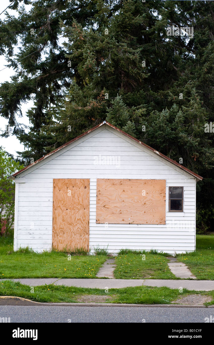 small white house with plywood covering door and window Stock Photo Alamy