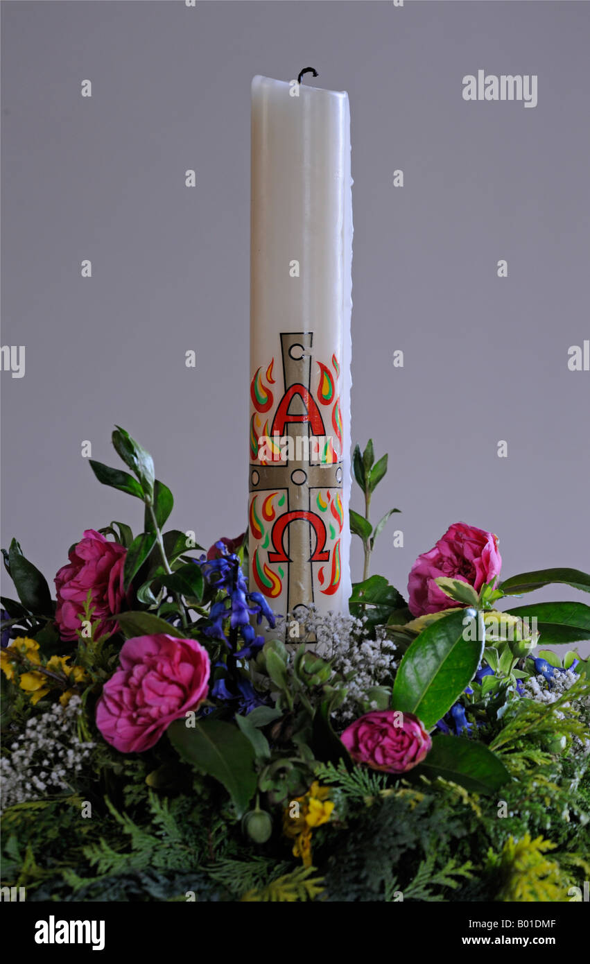 Baptismal candle with flowers . Holy Trinity Church , Winster . Lake District National Park , Cumbria , England , United Kingdom Stock Photo