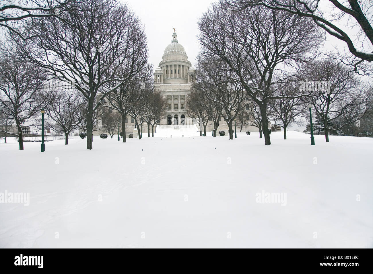 Photograph of the Rhode Island State House located in Providence.  Trees and snow line the walk to the building. Stock Photo