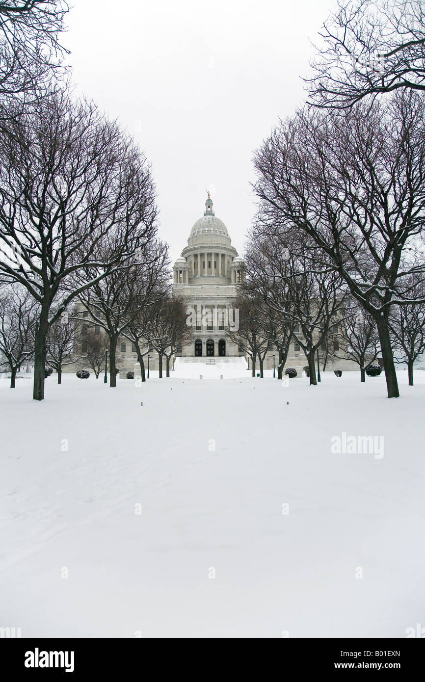Portrait photograph of the Rhode Island State House located in Providence.  Trees and snow line the walk to the building. Stock Photo