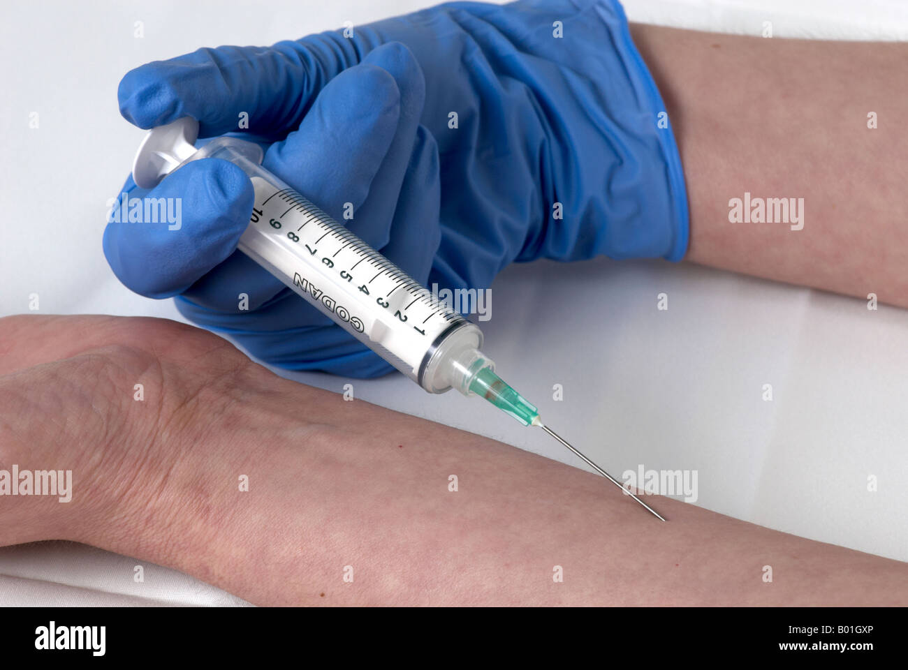 simulating the use of a needle in the arm by the same person with surgical gloves Stock Photo