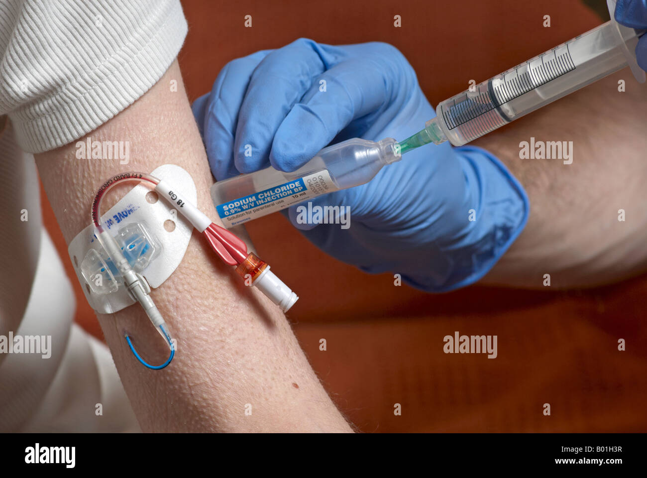 Using a syringe to withdraw sterile saline water from a vile