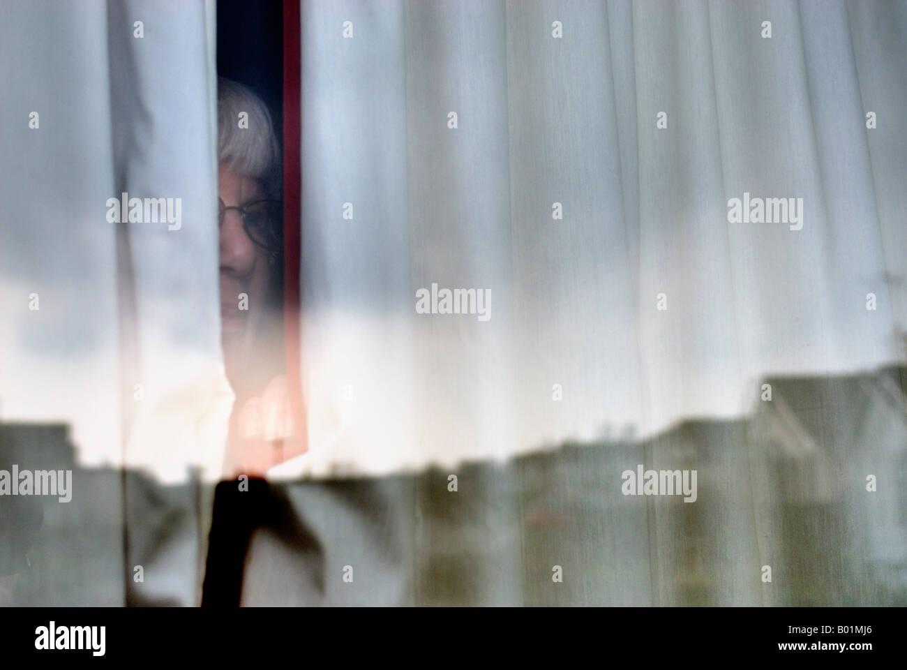 woman watching street through curtains Stock Photo