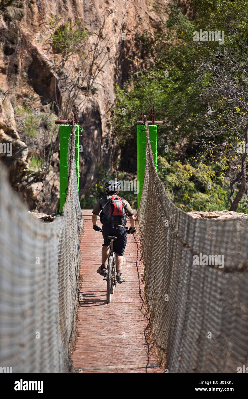 Coards mountain biking across a suspension bridge over the Rio Batopilas in the Copper Canyon