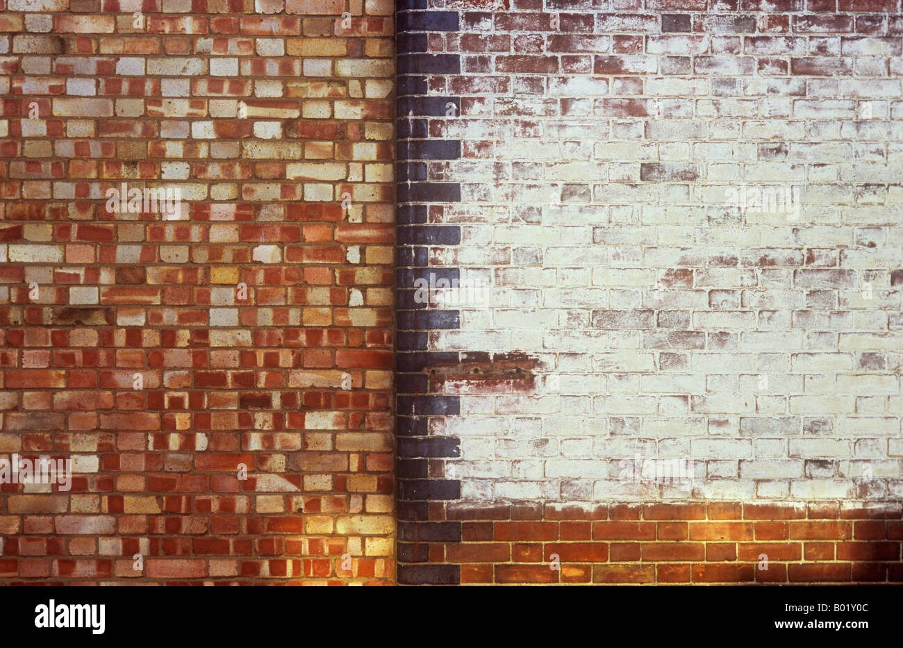Detail of once stylish brick wall painted white with rounded black edge bricks next to crudely bricked in doorway Stock Photo