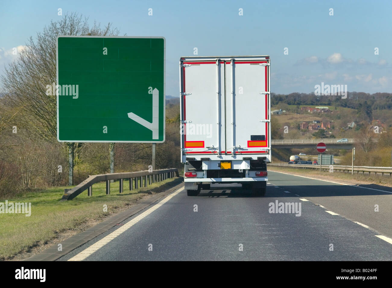 White heavy goods lorry passing a signpost on a dual carriageway blank for you to add your own text Stock Photo