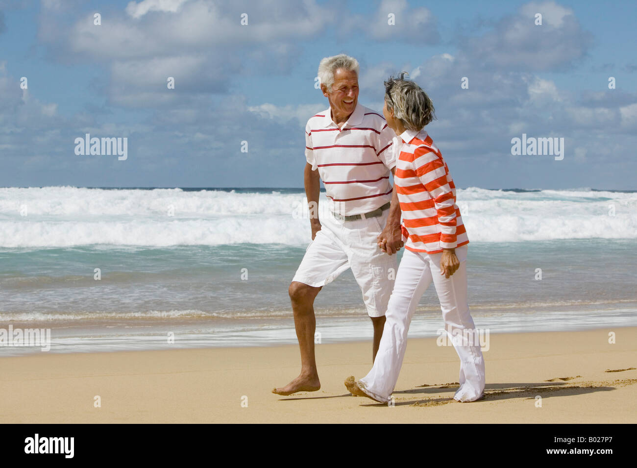 mature couple walking hand in hand along beach Stock Photo - Alamy