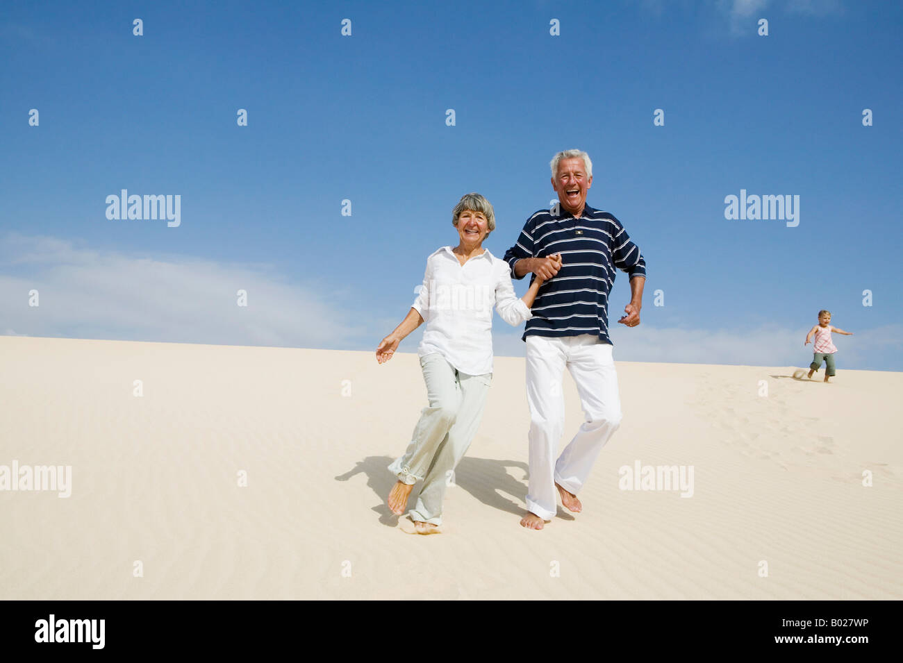 mature couple running down beach hand in hand Stock Photo - Alamy