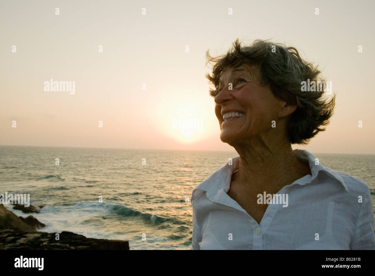 portrait of smiling mature woman on beach at sunset Stock Photo - Alamy