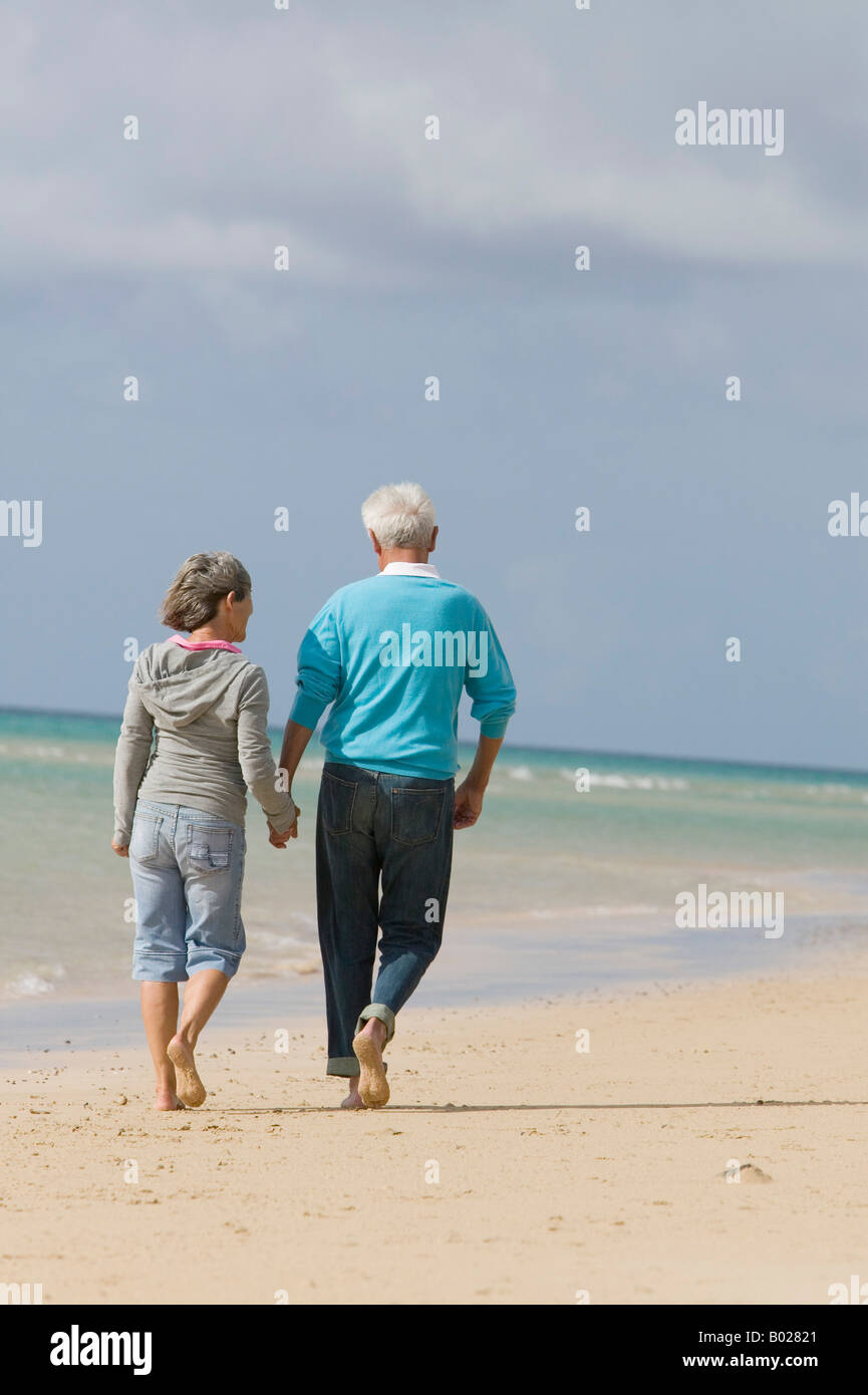 rear view of mature couple walking hand in hand along beach Stock Photo ...