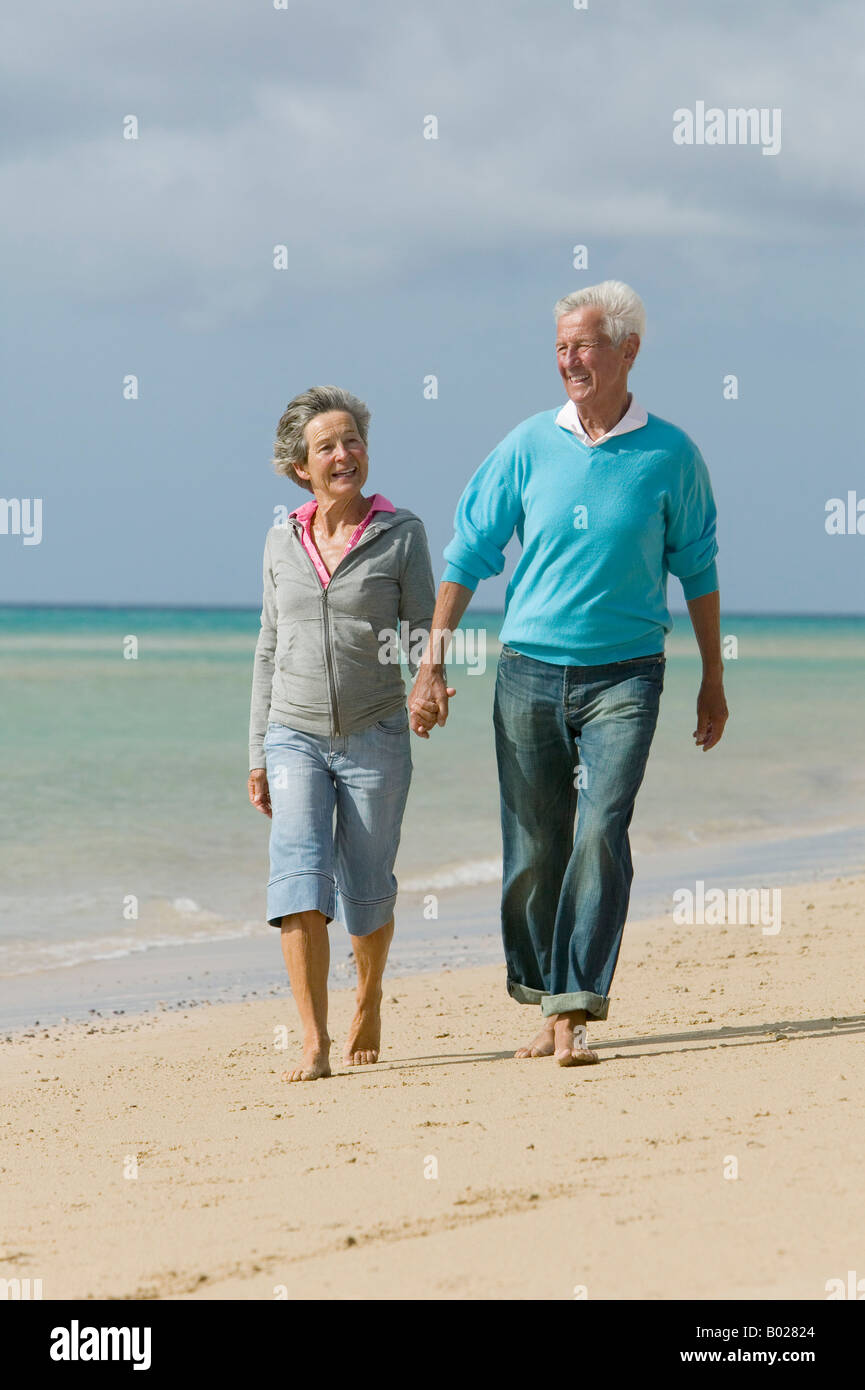 mature couple walking hand in hand along beach Stock Photo - Alamy