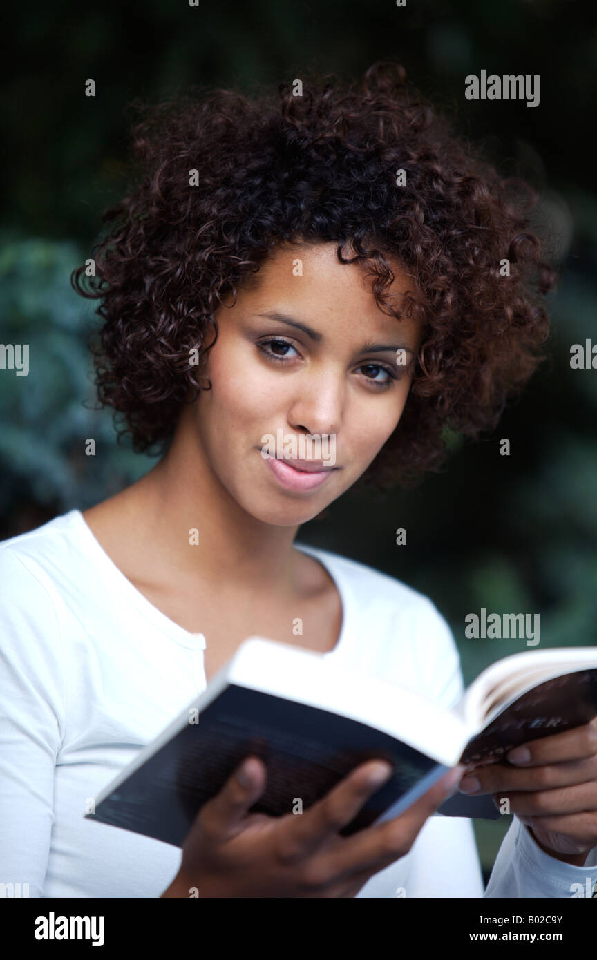 ethnic girl - half German half Cuban - sits in a park and reads a book Stock Photo