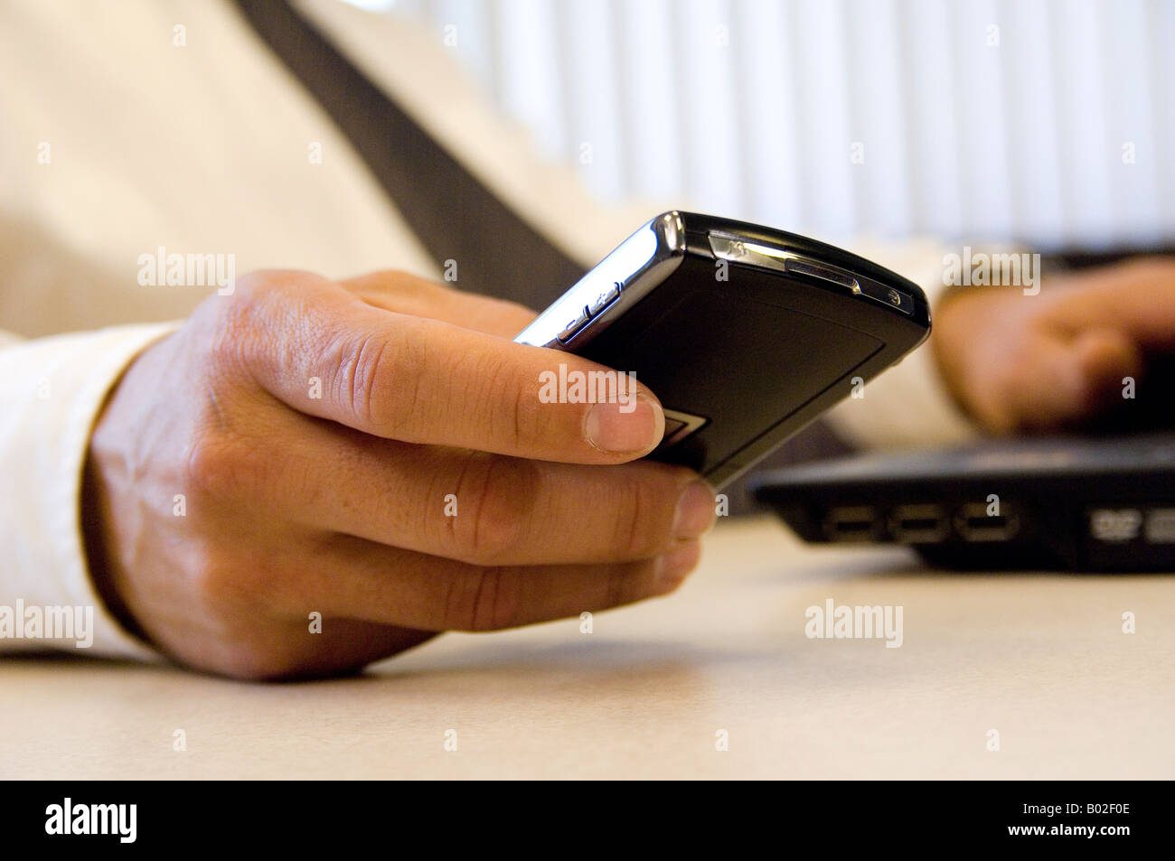 Close-up of male executive's hand sending message on  blackberry PDA device. Stock Photo