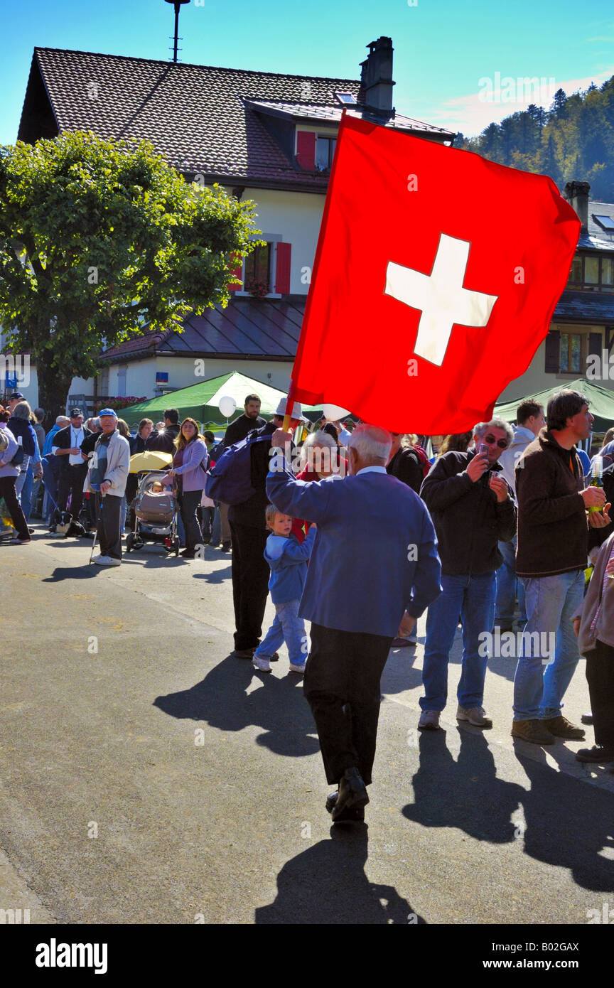 A Swiss flag-thrower parading his flag through the crowds at a 'desalpe' festival. Stock Photo