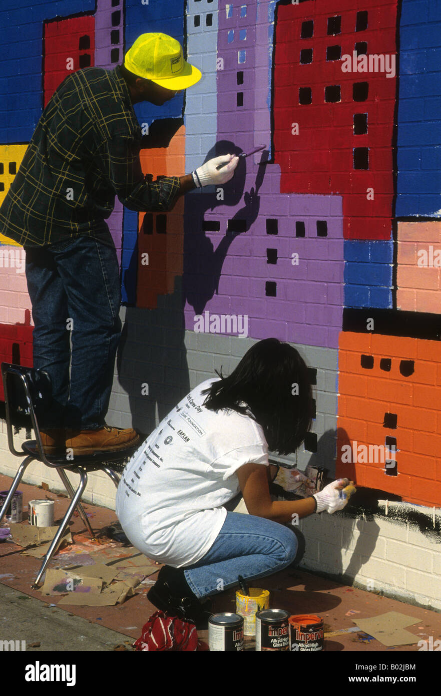 Volunteers from New York Cares paint a mural in a New York public school Stock Photo
