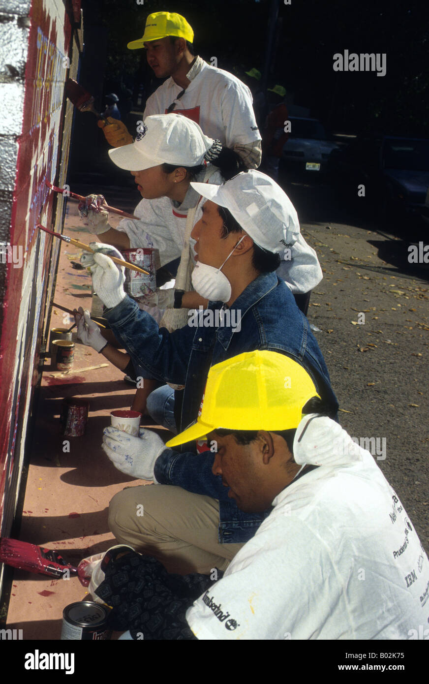 Volunteers from New York Cares paint a mural in a New York public school Stock Photo