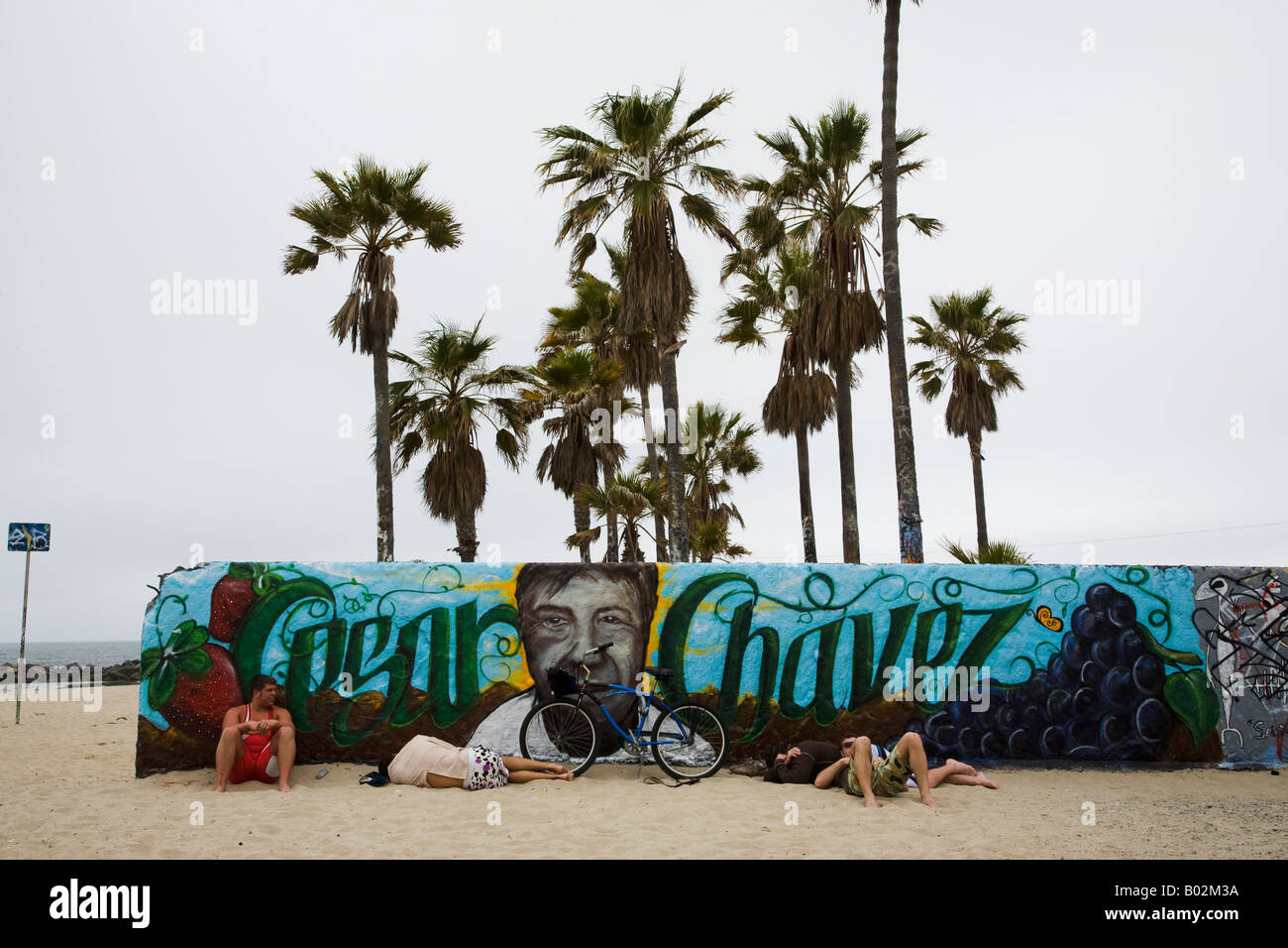 Bike riders rest and nap at a mural of Cesar Chavez Venice Beach Los Angeles California United States of America Stock Photo