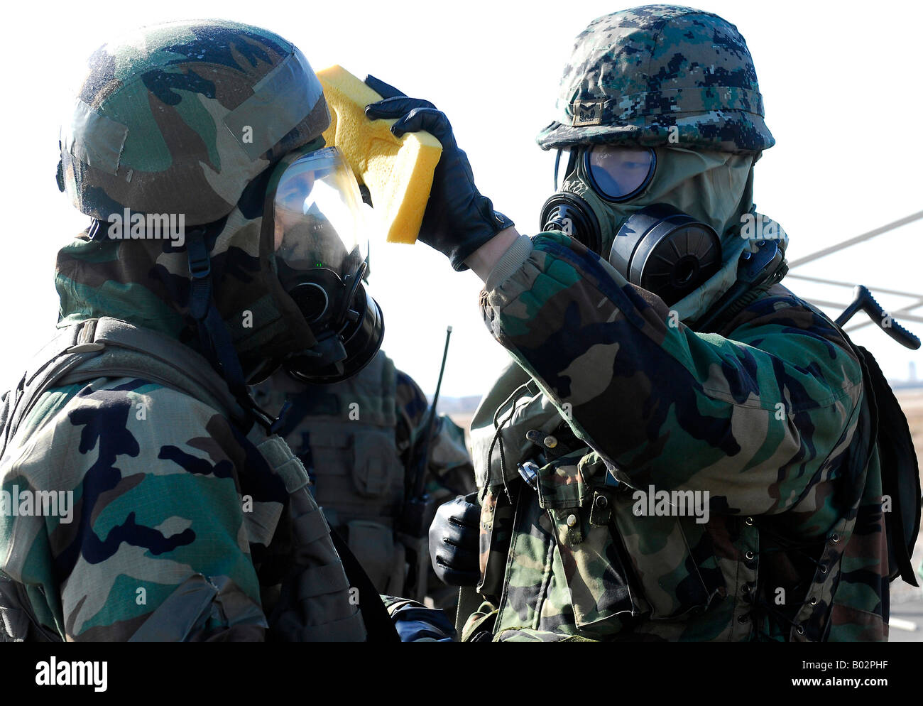 A soldier assisting a fellow soldier during a decontamination process. Stock Photo