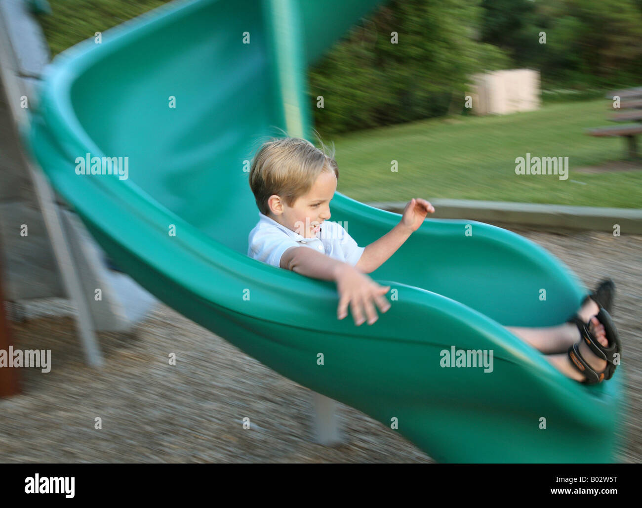young boy sliding down a playground slide at a park Stock Photo Alamy