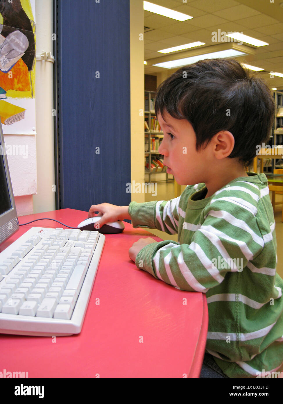 Little boy behind a computer in the library Stock Photo - Alamy