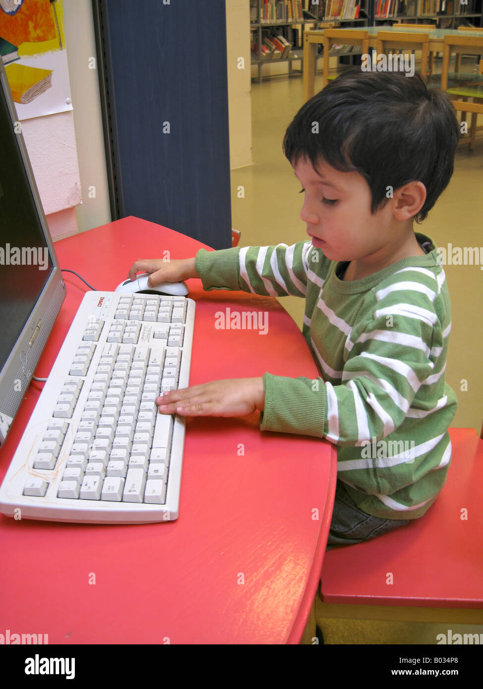 Little boy behind a computer in the library Stock Photo - Alamy