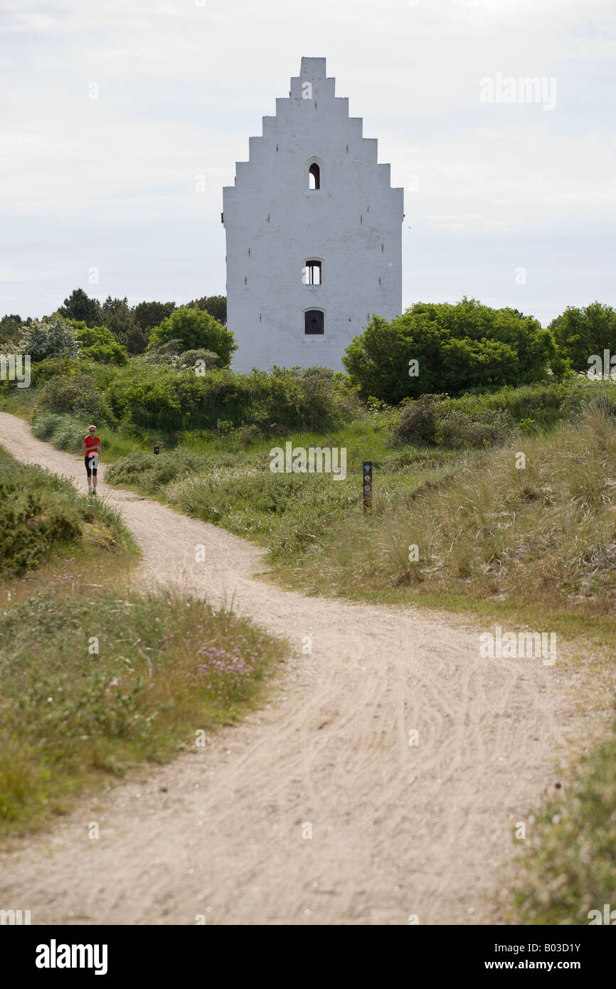 Jogging By A woman in red jogs by the famous church partially buried in the dune sands near Skagen Stock Photo