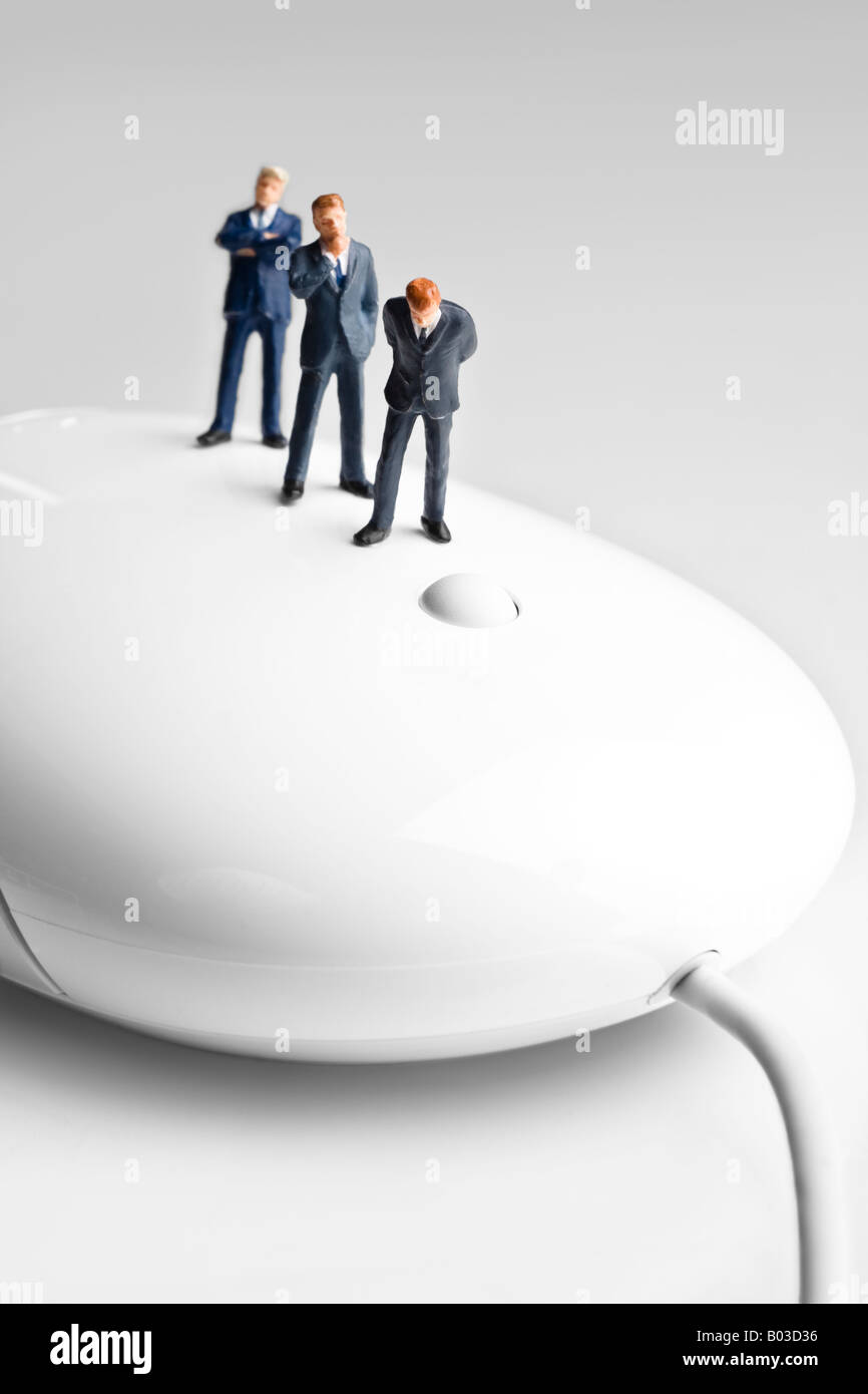 Businessman figurines standing on a computer mouse Stock Photo